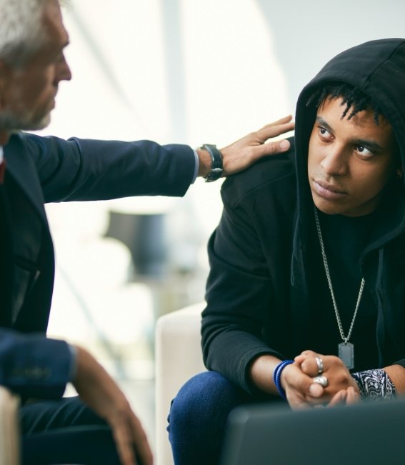 African American teenage boy having individual therapy session with mental health professional.