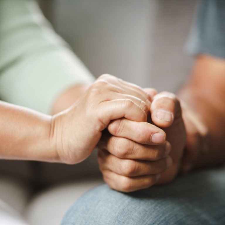 Female friend or family sitting and hold hands during cheer up to mental depress man, Psychologist provides mental aid to patient. PTSD Mental health concept