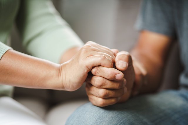 Female friend or family sitting and hold hands during cheer up to mental depress man, Psychologist provides mental aid to patient. PTSD Mental health concept