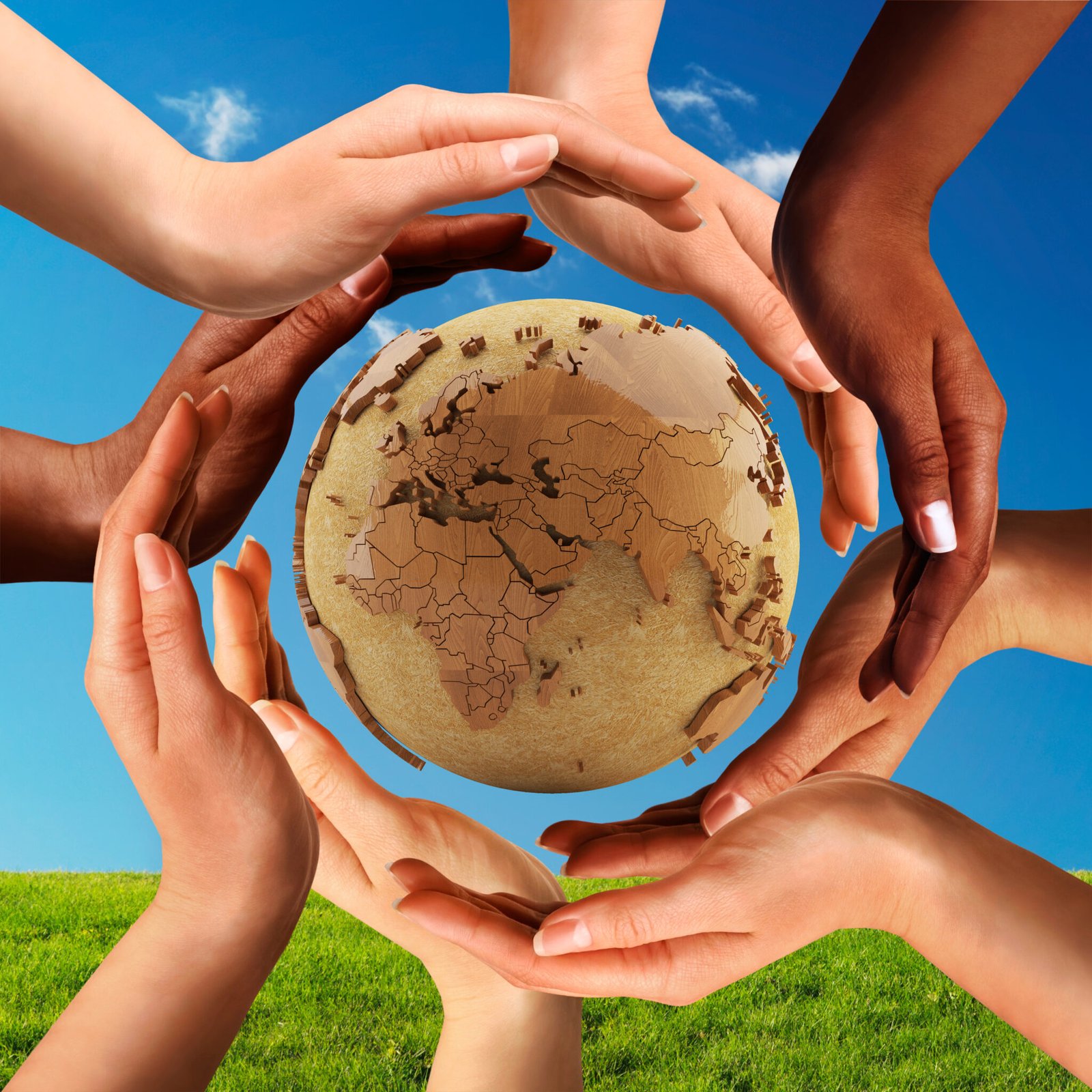 Conceptual peace and cultural diversity symbol of multiracial hands making a circle together around the world the Earth globe on blue sky and green grass background.