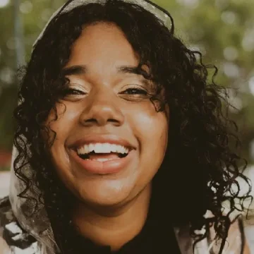 Jasmin Duany, patóloga del habla y lenguaje, sonriendo bajo la lluvia con un impermeable transparente